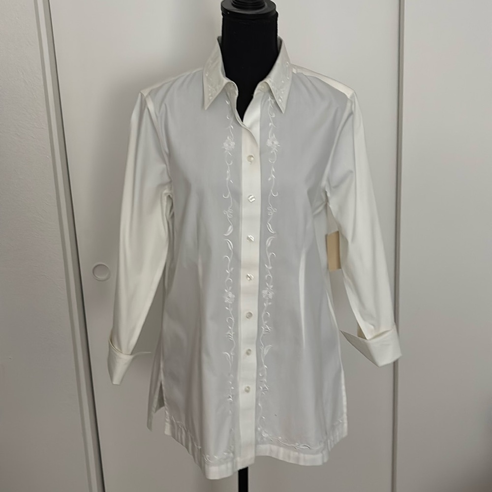 White blouse with embroidered trim and cuffed sleeves.